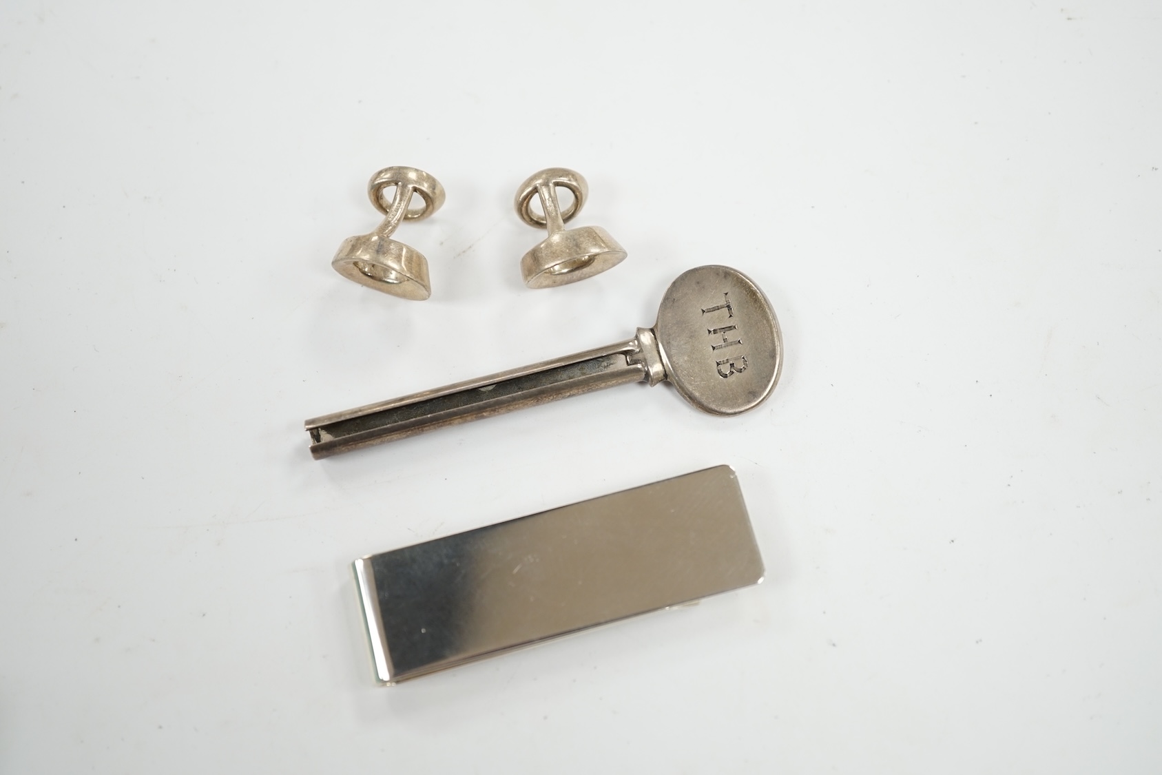 A group of Tiffany & Co sterling novelties; a pair of Frank Gehry Morph cufflinks, a toothpaste winder and a money clip, 57mm. Condition - fair to good